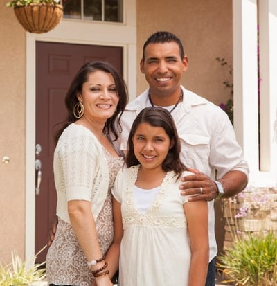 Smiling family of three standing in front of texas home
